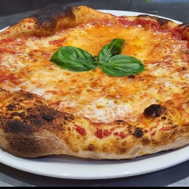 Pizza Margherita con il cornicione alto e una foglia di basilico