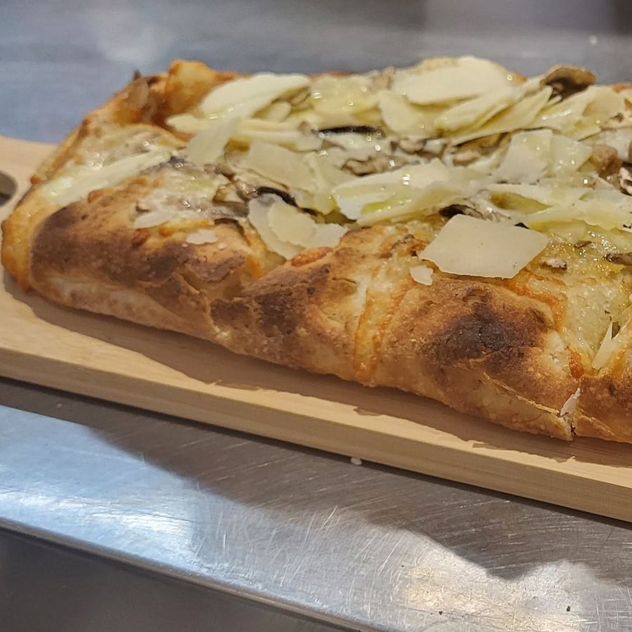 Una pizza in pala scrocchiarella appena sfornata, su un tagliere di legno